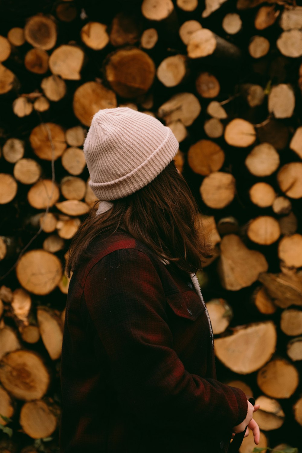 a woman standing in front of a pile of logs