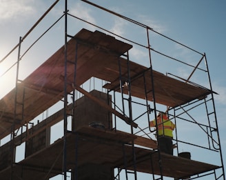 a construction worker standing on a scaffold in front of the sun