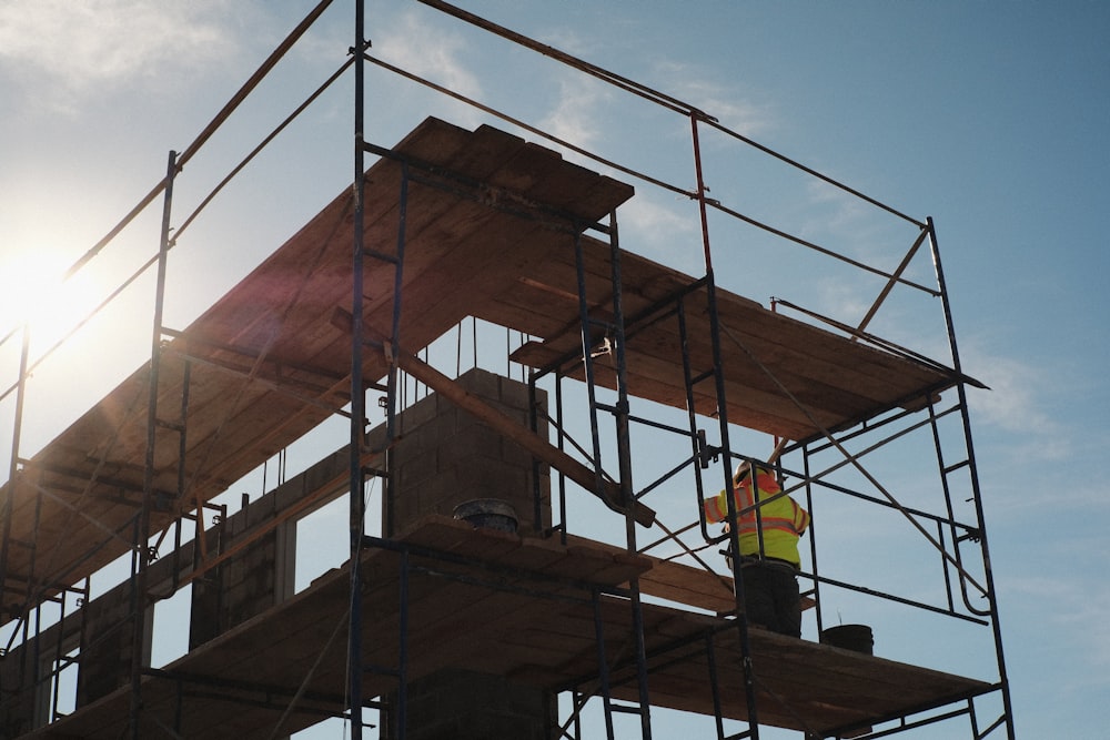 a construction worker standing on a scaffold in front of the sun