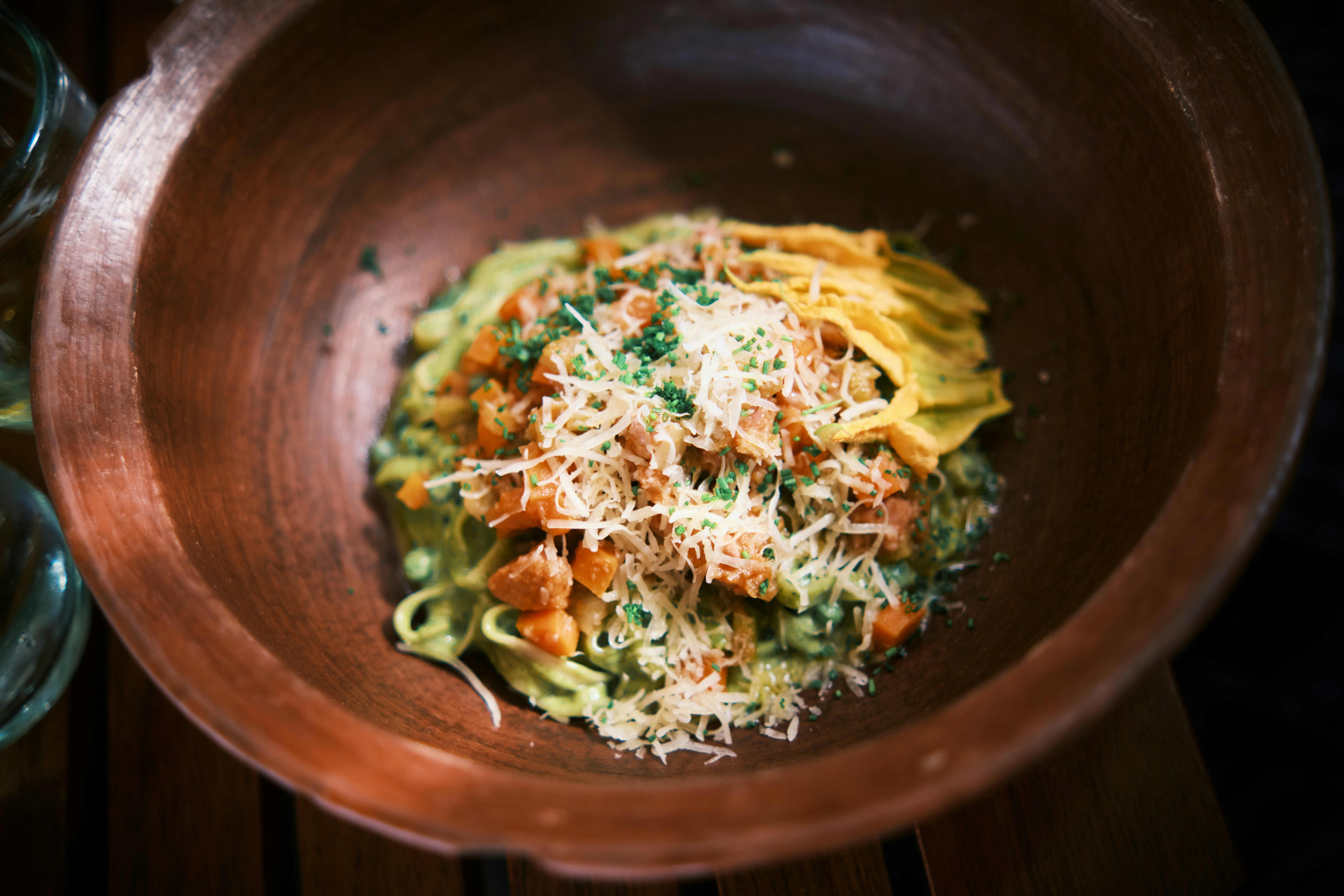 a wooden bowl filled with pasta and vegetables, 