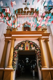 A welcoming church entrance with the sign 'Jesús te ama' visible, surrounded by green plants and sunlight.