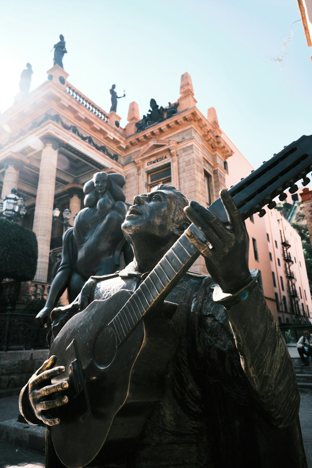 a statue of a man playing a guitar in front of a building