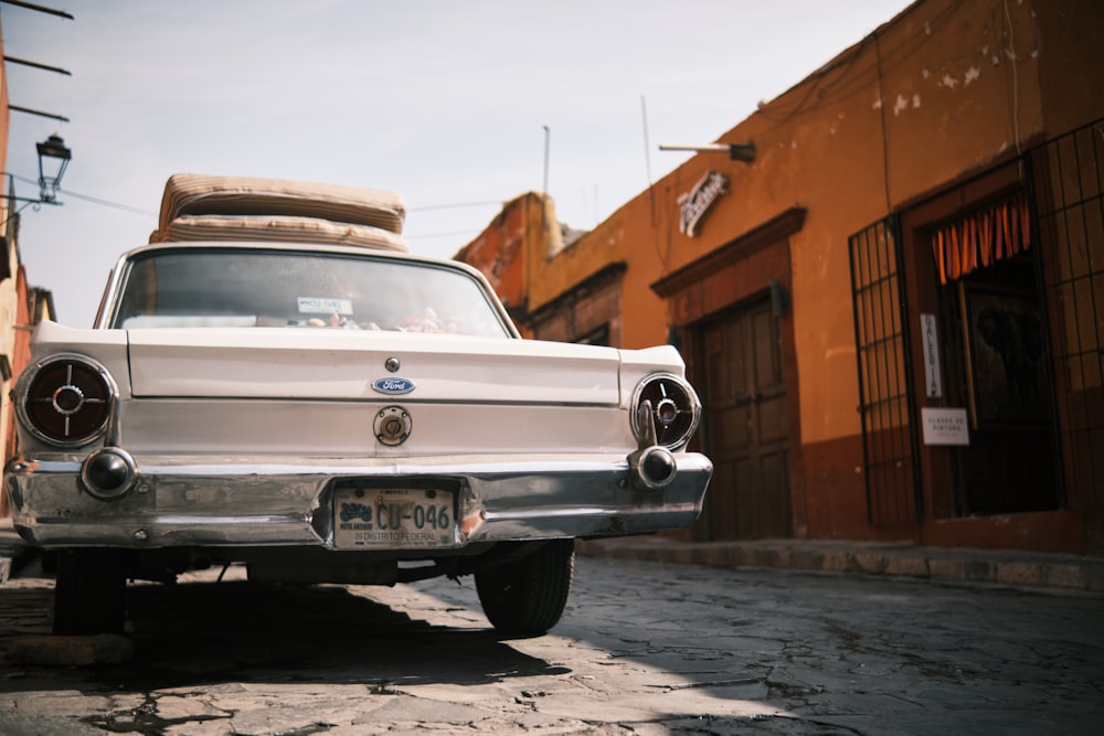 an old white car with luggage on top of it