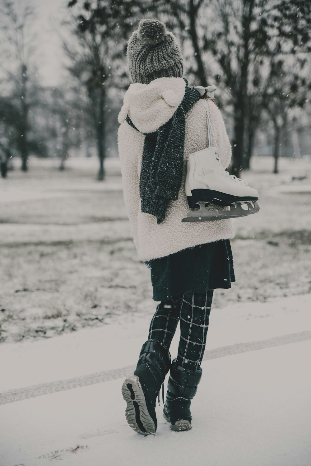 a woman walking in the snow carrying a snowboard