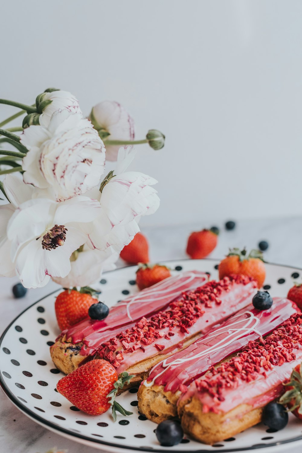 a piece of cake on a plate with strawberries and blueberries