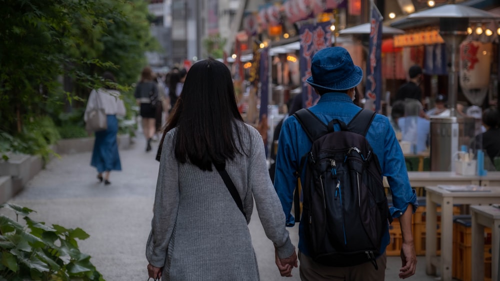 a man and a woman walking down a street holding hands