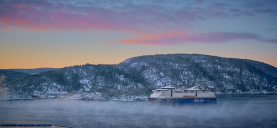 A serene cruise ship sailing past an Alaskan glacier under a soft sunset.
