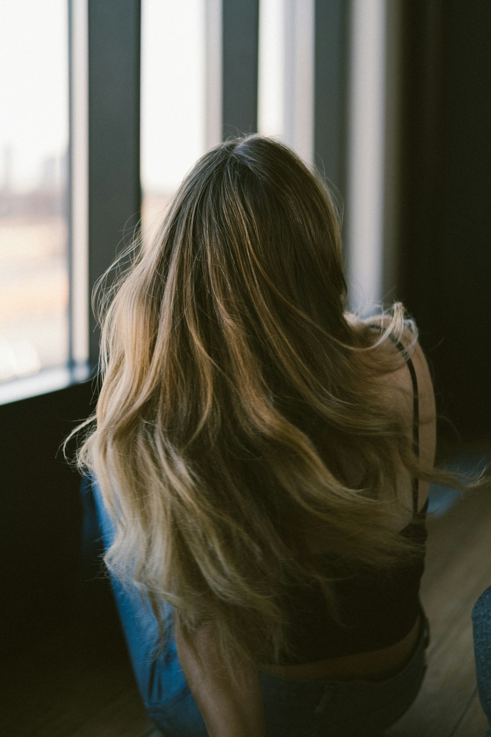 a woman sitting on the floor looking out a window