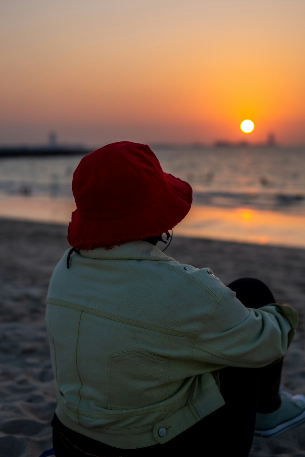 Una persona sentada en una playa viendo la puesta de sol