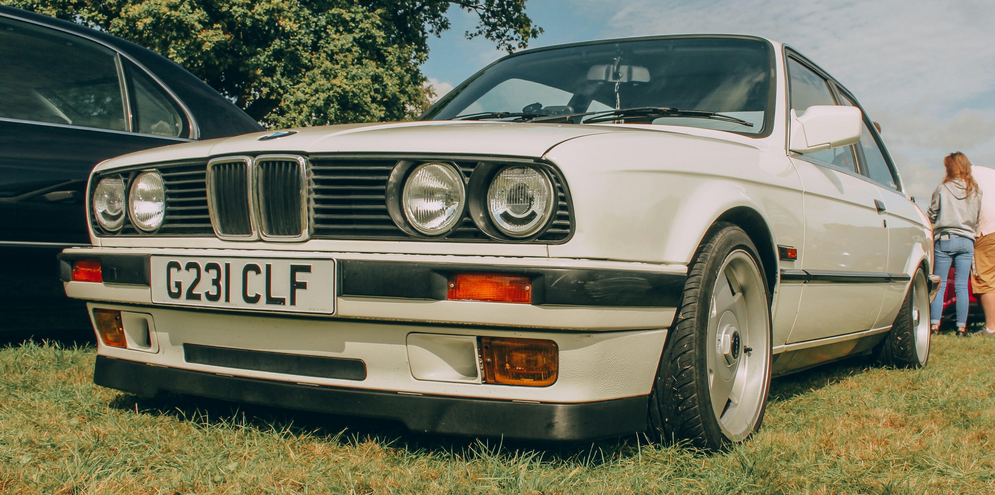 a couple of people standing next to a white car