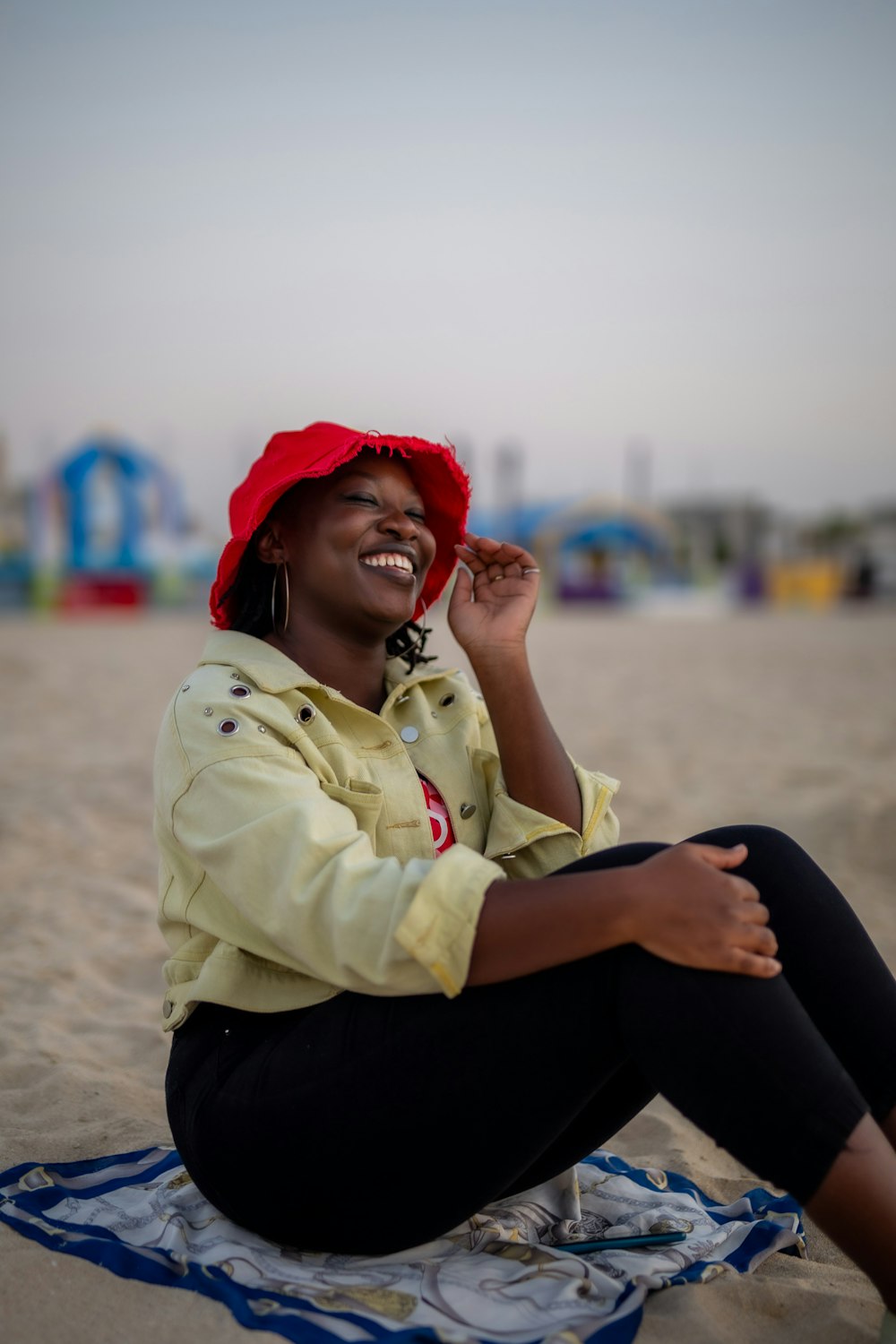 a woman sitting on top of a blanket on top of a beach