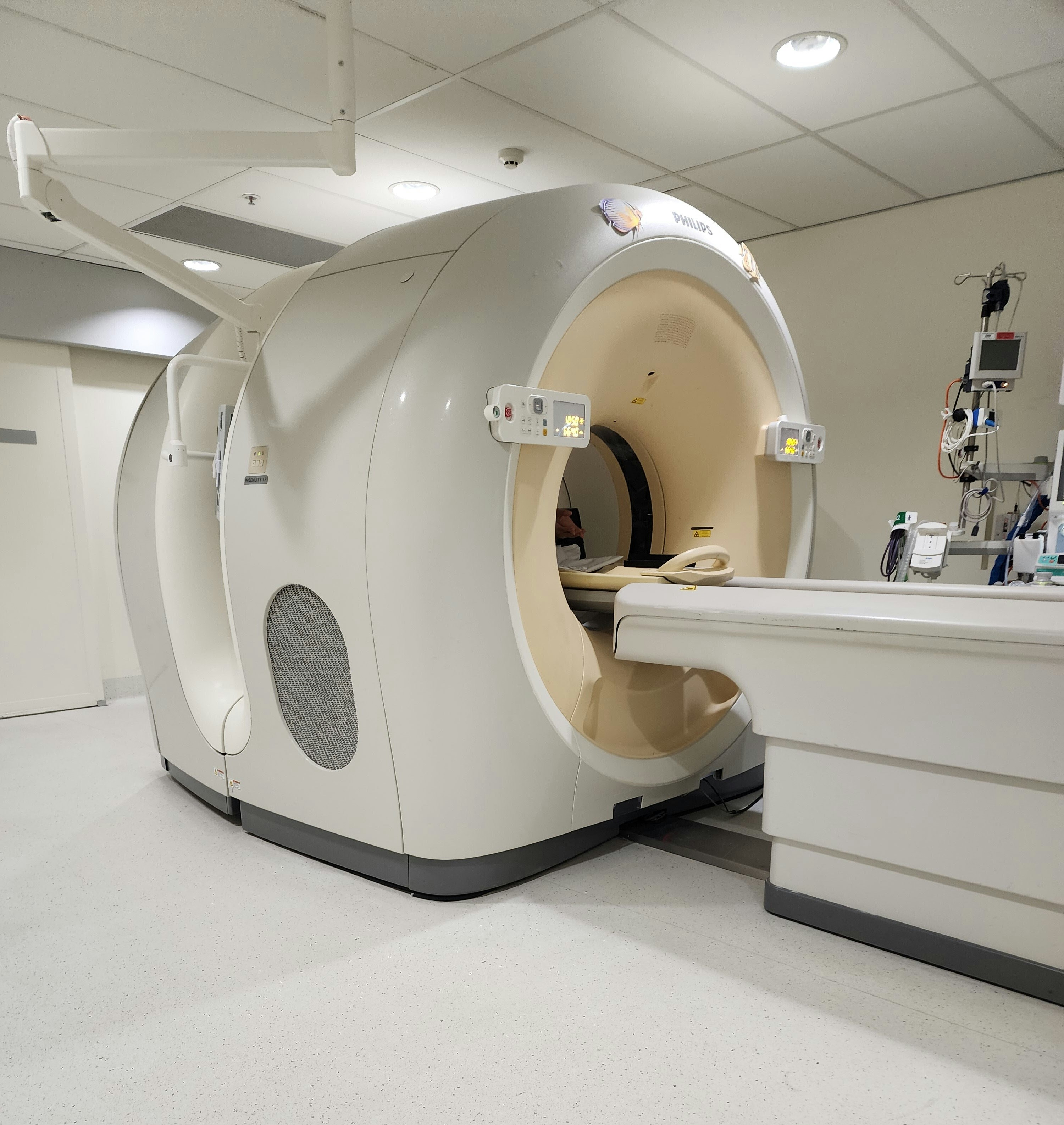 Advanced CT scanner machine in dark medical facility, blue-white equipment lighting, deep shadows, high-tech clinical environment