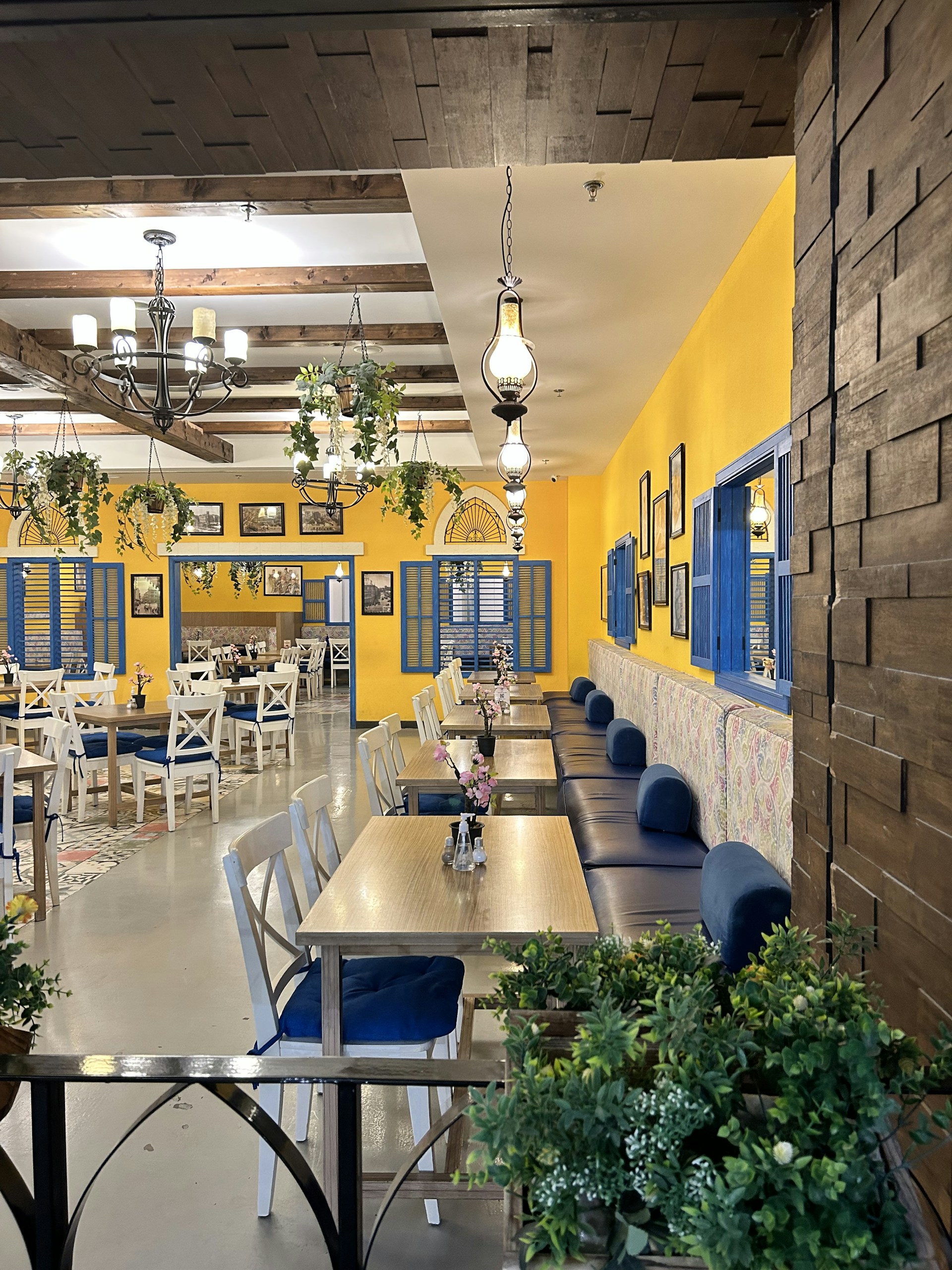 Warm, inviting interior of menuee restaurant with dark brown and yellow baroque decor and cozy wooden tables.