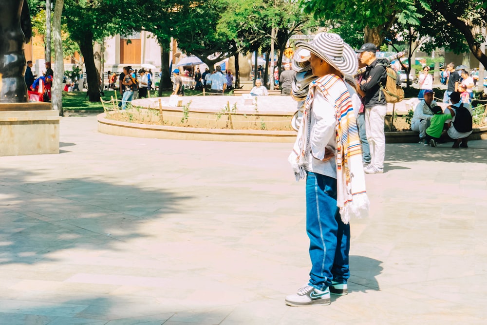 a woman standing in a park with a hat on