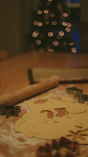 A cozy kitchen scene showing hands decorating a batch of homemade cookies