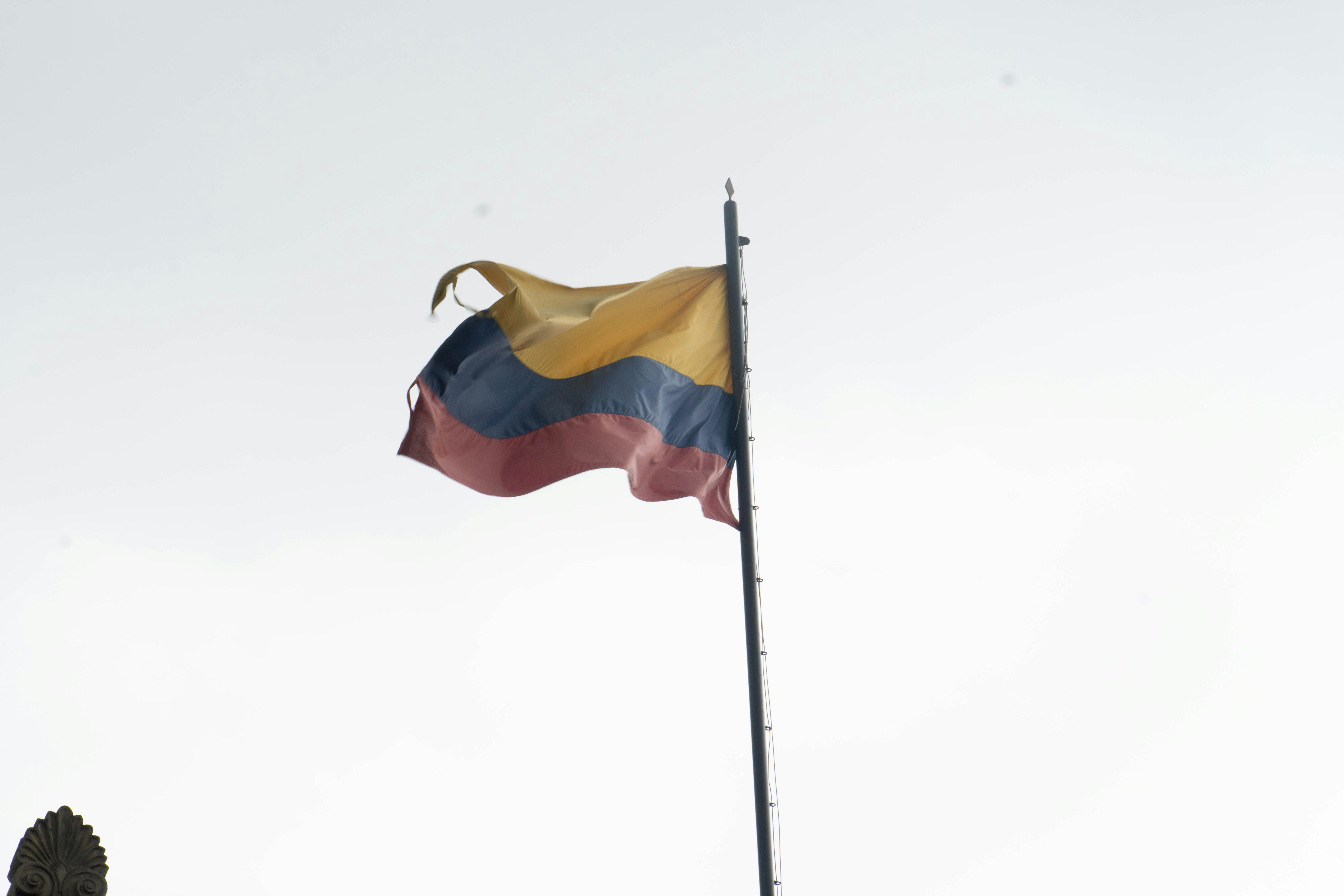 Colombian flag waving against a clear blue sky, bright sunlight, patriotic atmosphere