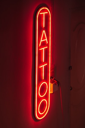A vibrant neon tattoo glowing brightly on a forearm in a dark setting.