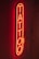 A bright red neon sign displaying the word 'TATTOO' vertically on a dark background, creating a glowing effect that highlights the word against the wall.