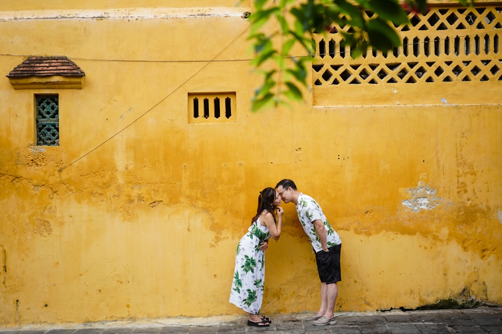 a couple of women standing next to a yellow wall