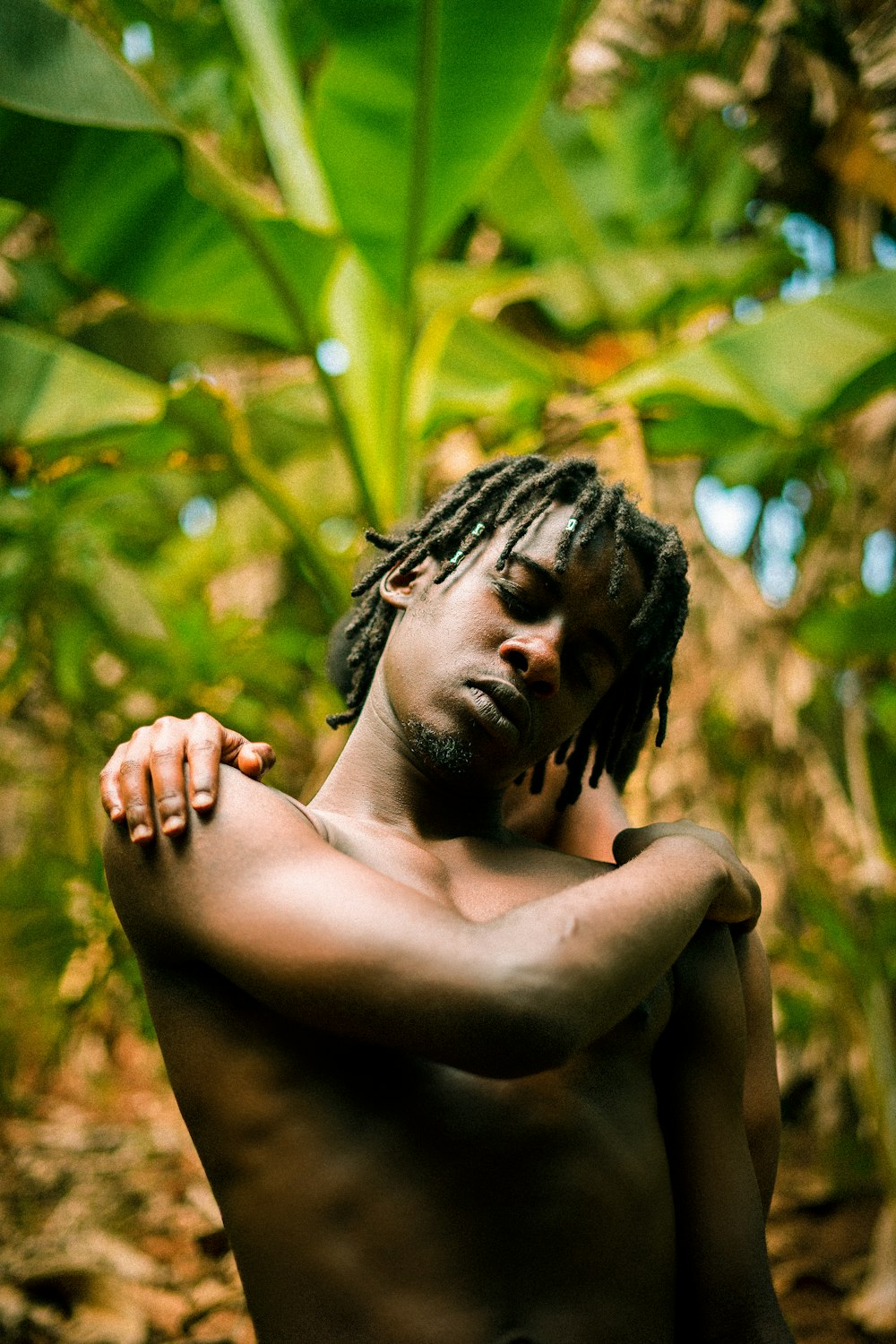 a man with dreadlocks standing in a jungle