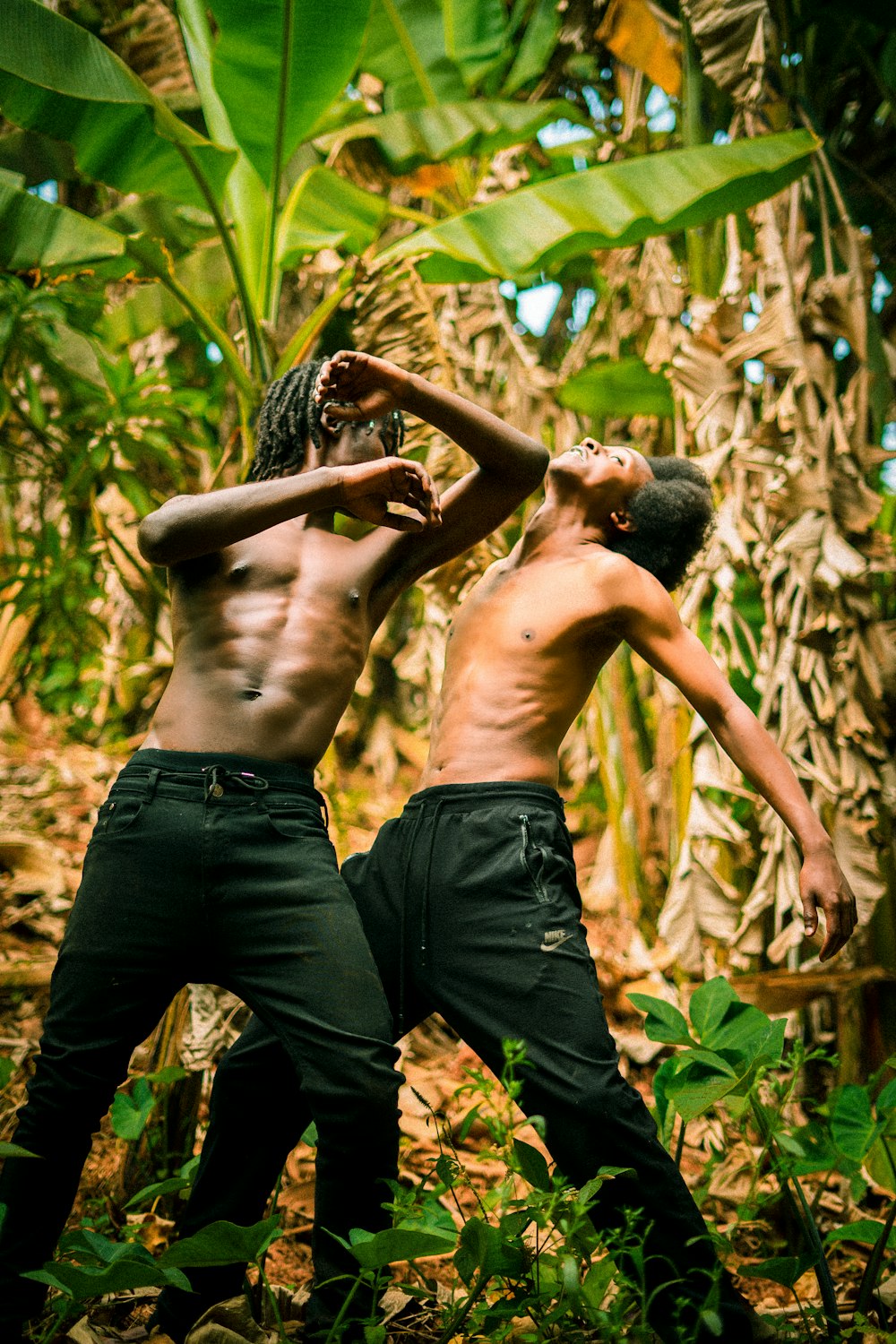 a couple of men standing next to each other in a forest