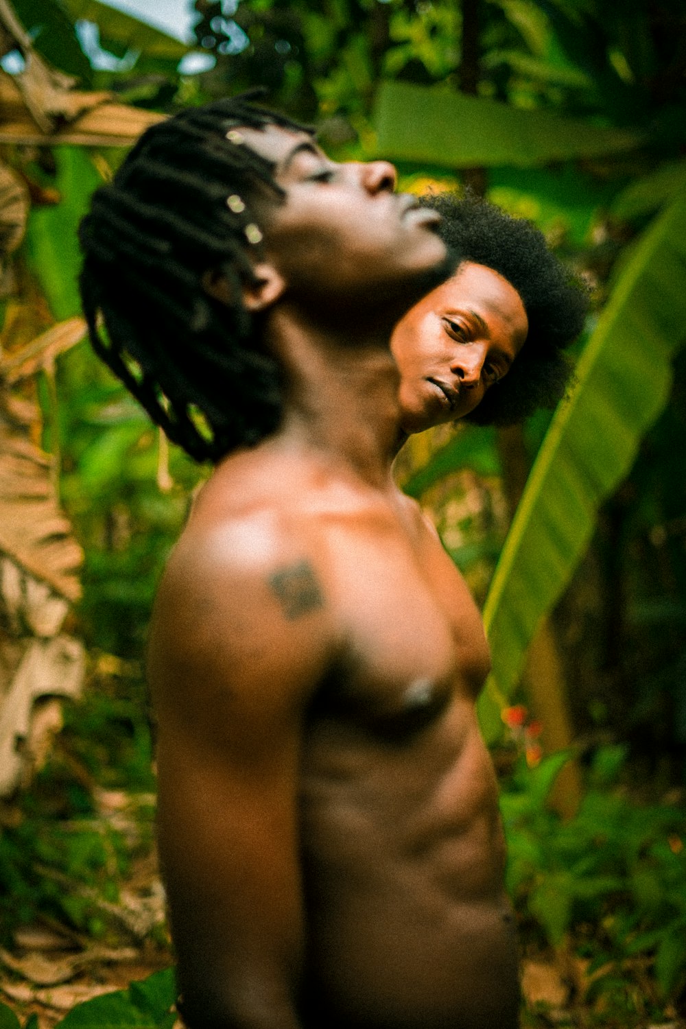 a man with no shirt standing in a jungle