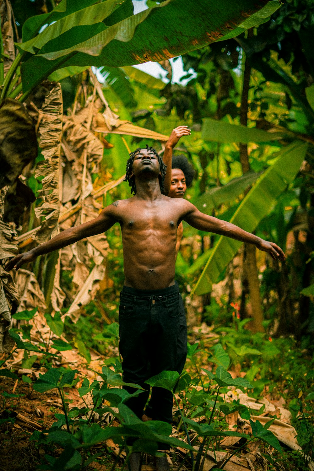 a man holding a stick in the middle of a jungle