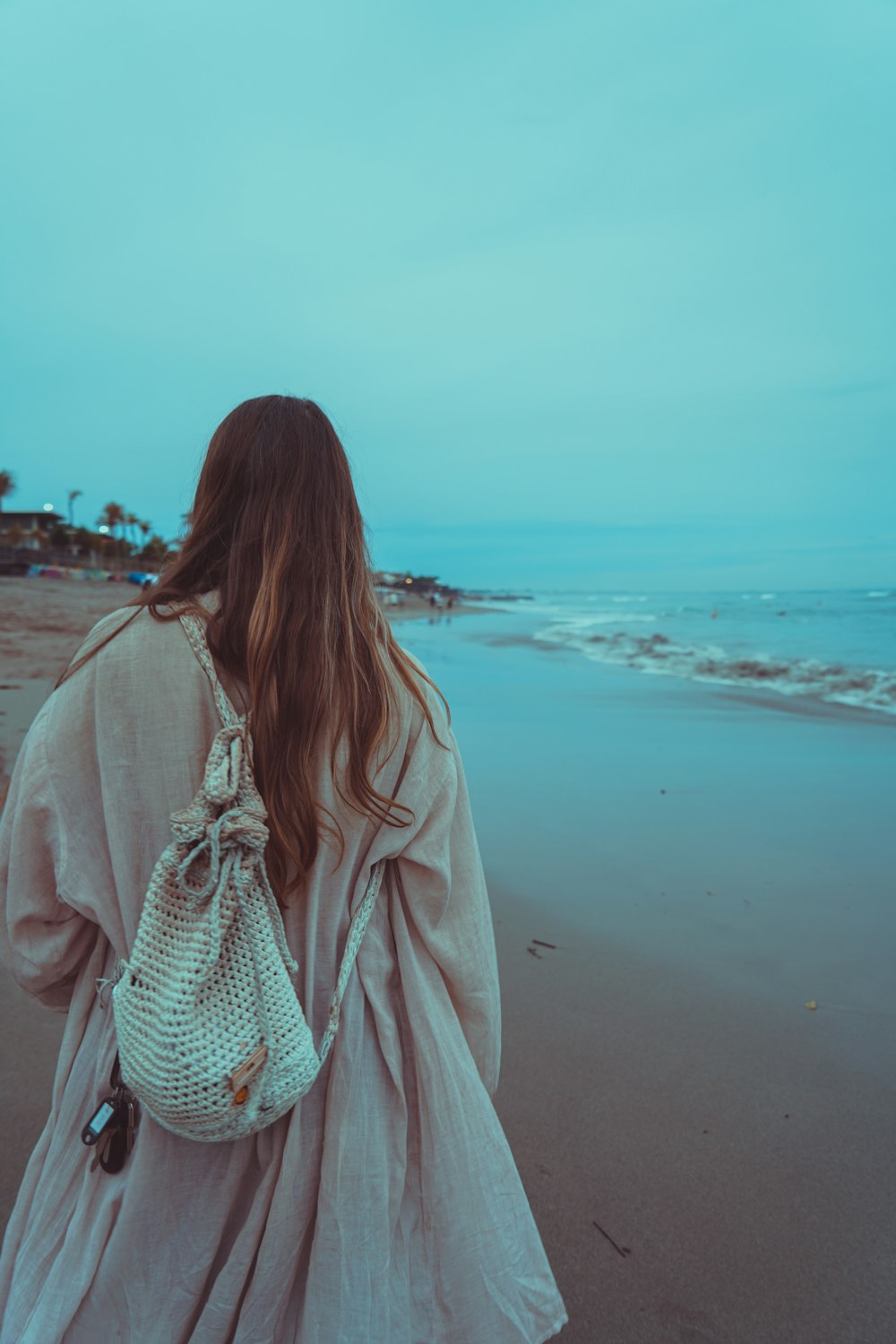 a woman walking on a beach carrying a purse