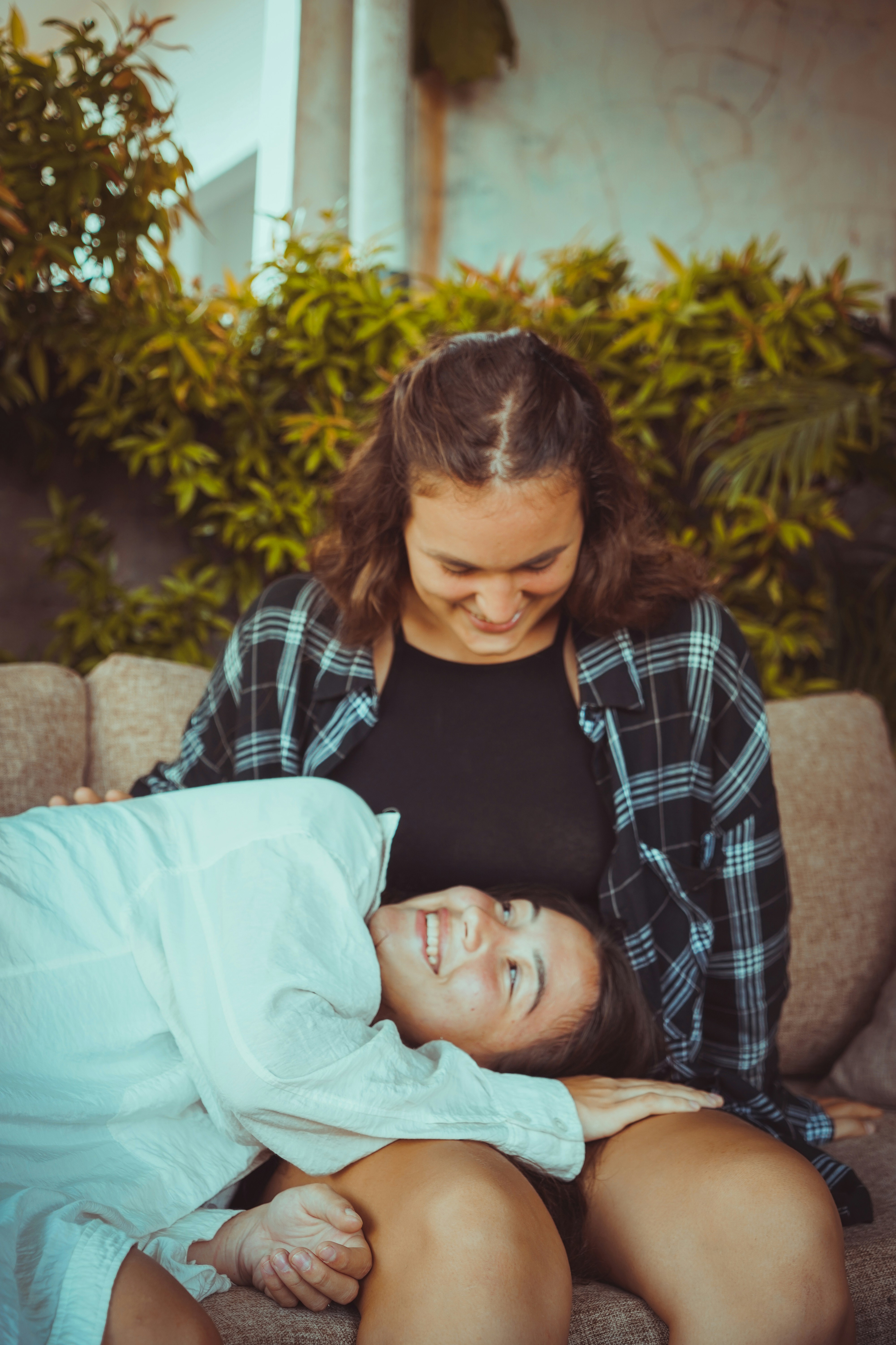 a woman laying on top of a woman on a couch
