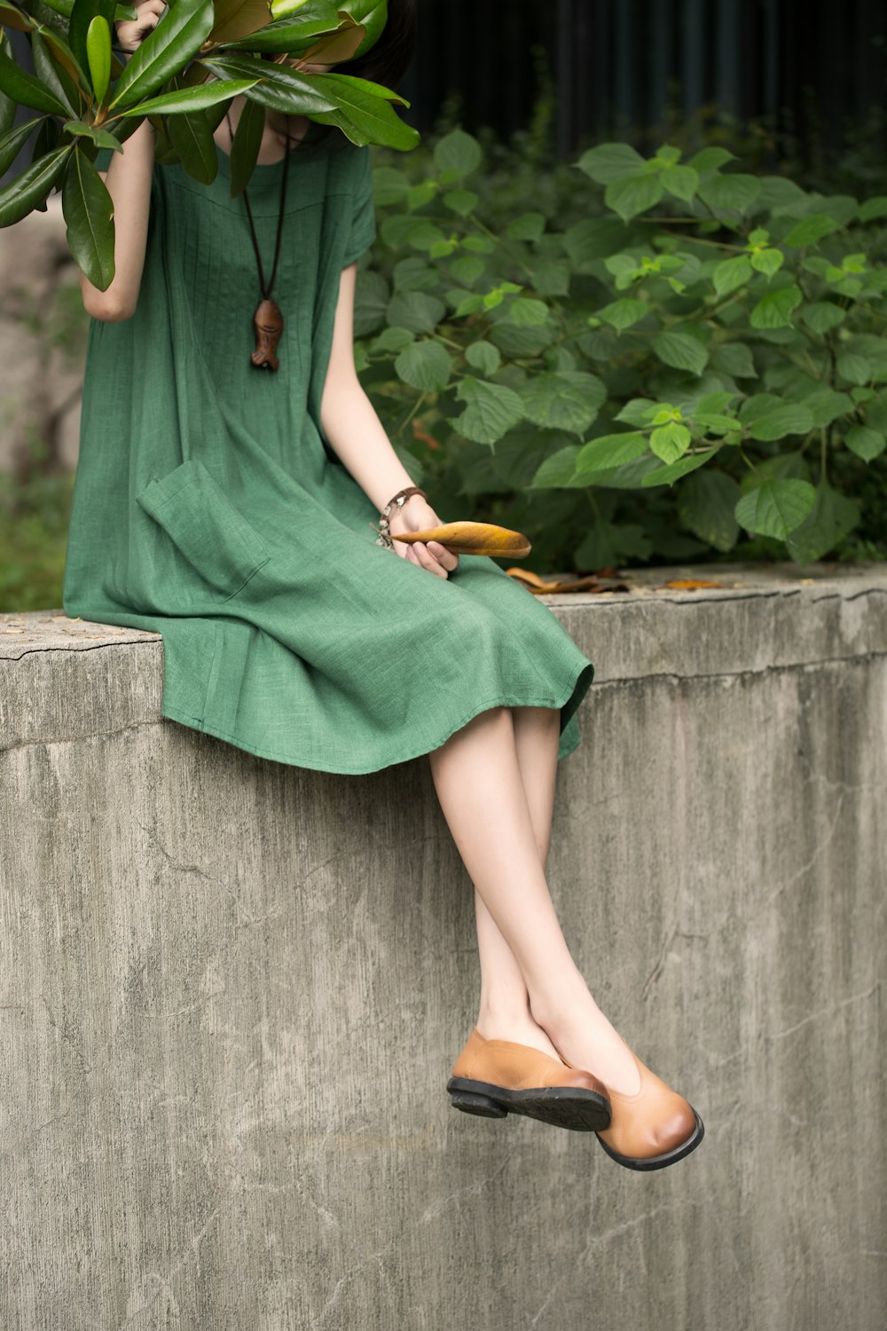 a woman in a green dress sitting on a wall