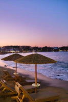 Sunset over a lively beach club with turquoise waters and white lounge chairs