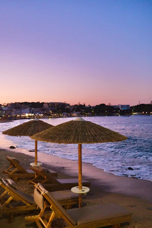 Sunset over a lively beach club with turquoise waters and white lounge chairs