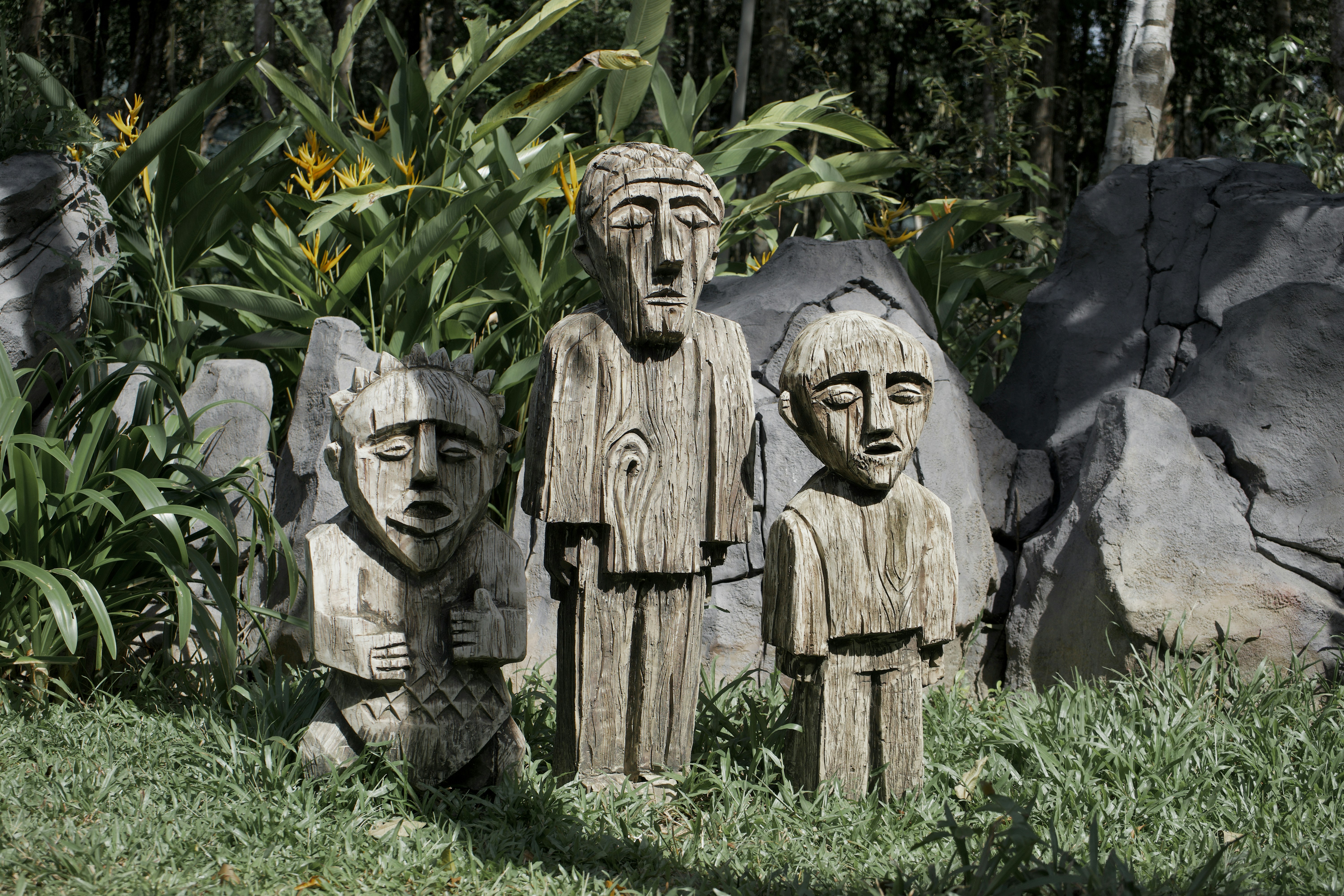 un groupe de personnages en bois sculpté assis au sommet d’un champ verdoyant