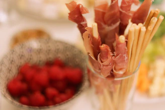 A close-up shot of warm breadsticks served with a creamy herb dipping sauce next to a sparkling glass of white wine.
