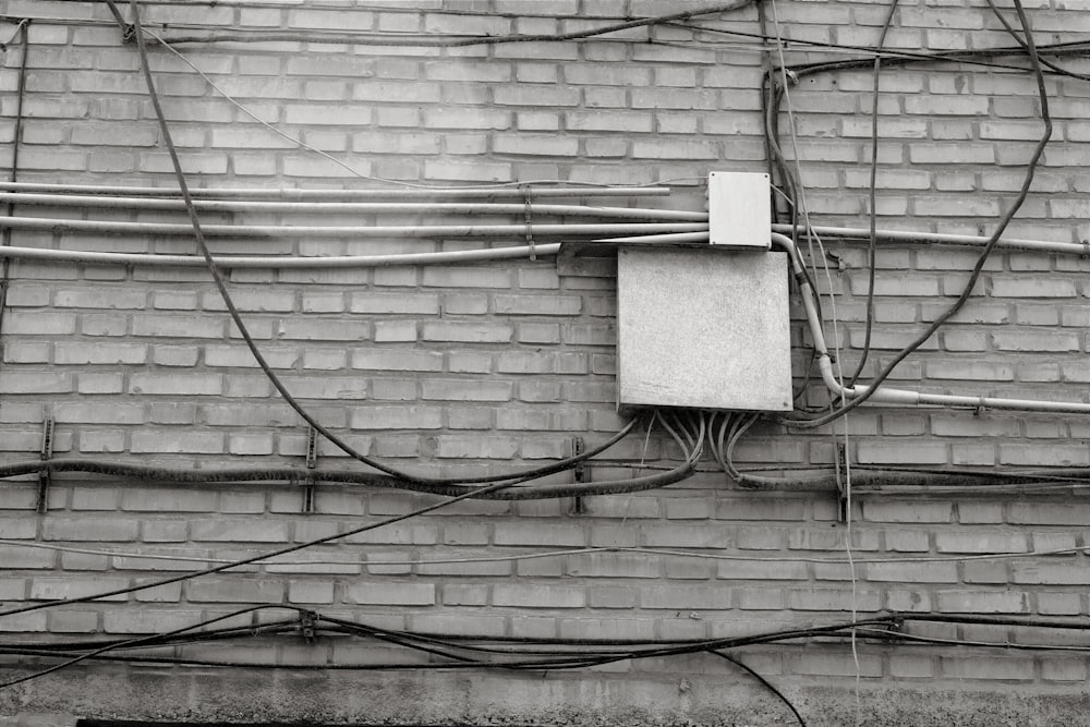 a black and white photo of an electrical box on a brick wall