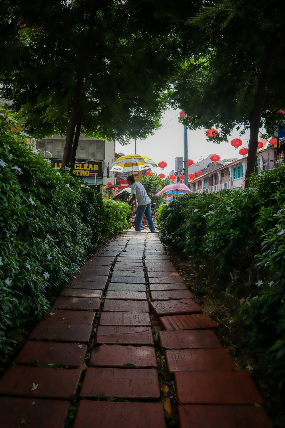 a man walking down a brick path with an umbrella
