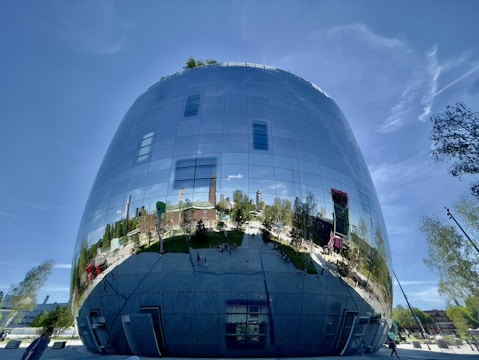A sleek commercial building with green rooftop gardens and large glass windows reflecting the city skyline.