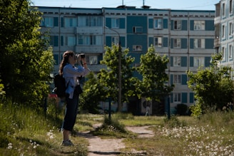 A private investigator observing a subject through binoculars in an urban setting.