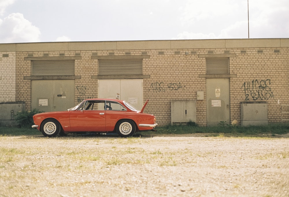 a red car parked in front of a brick building