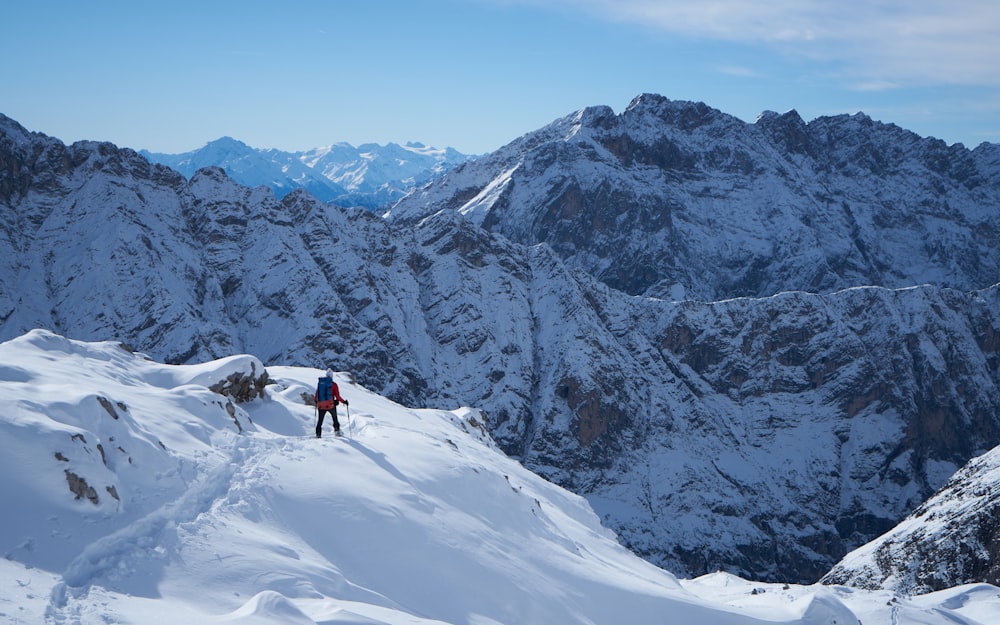 Un uomo che cammina sul fianco di una montagna coperta di neve