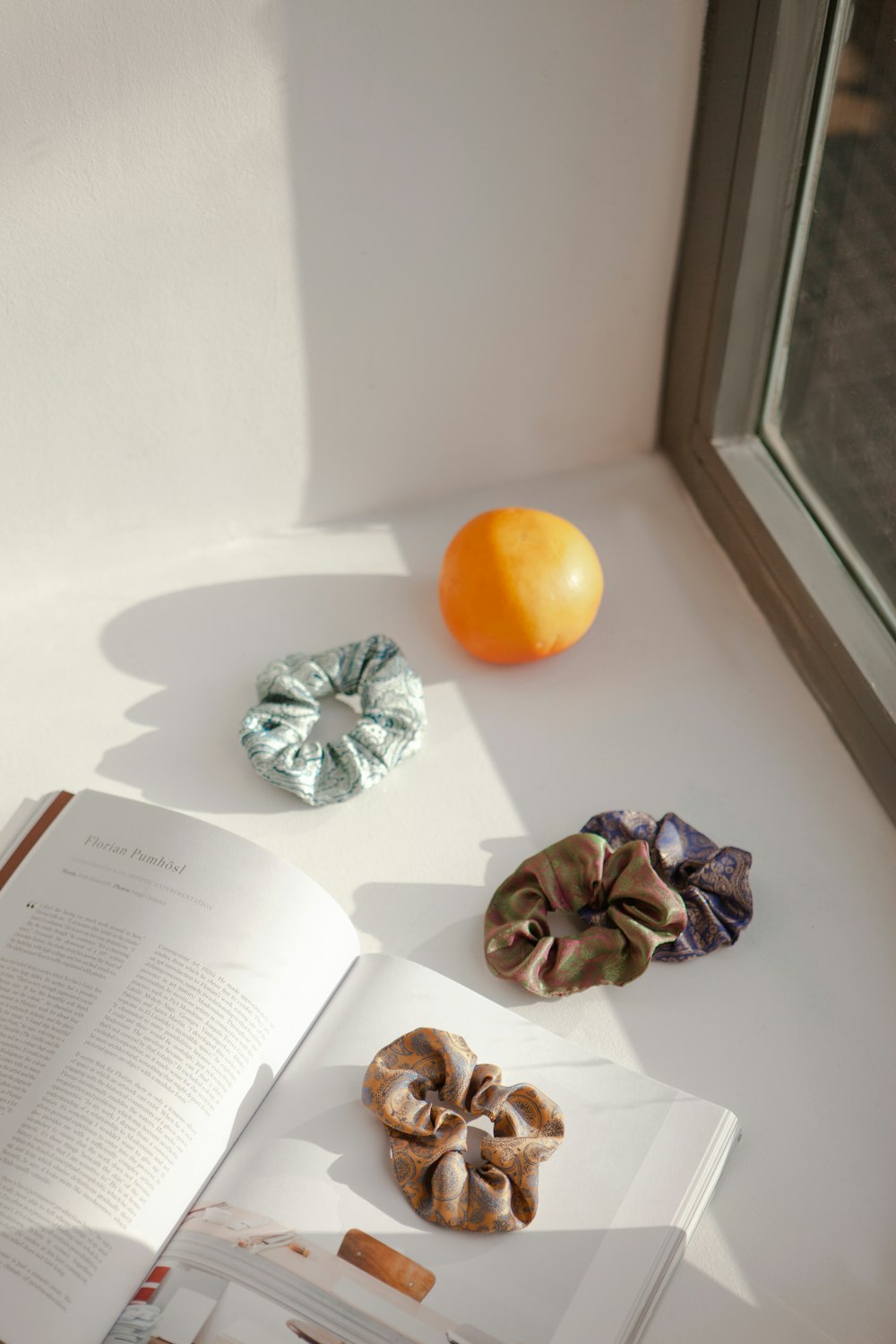 Un libro aperto seduto sopra un tavolo accanto a un'arancia