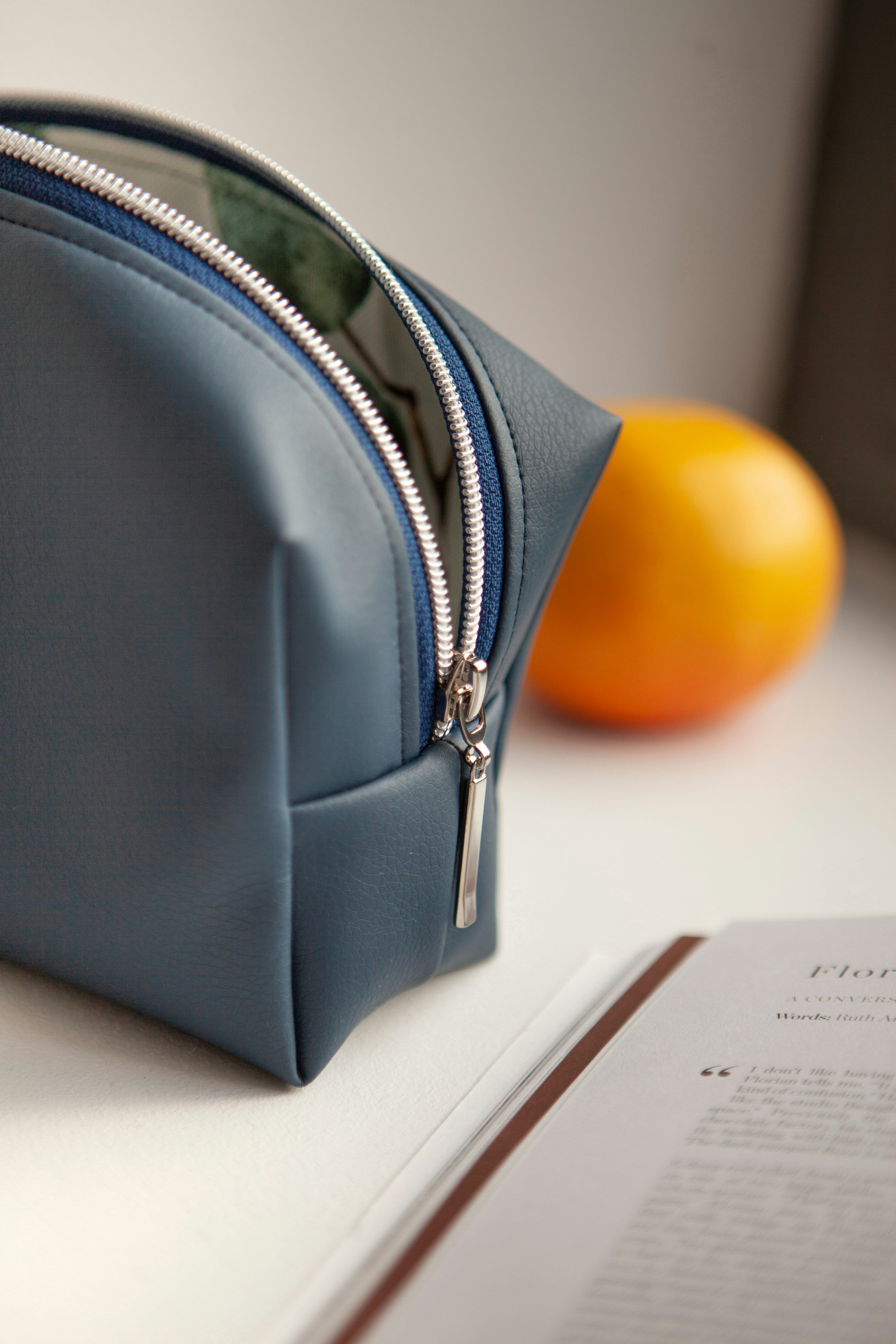 Un bolso azul sentado encima de una mesa junto a una naranja