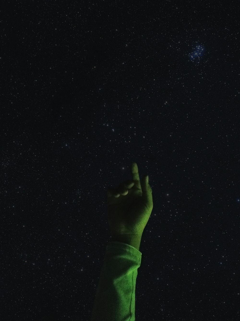 a hand reaching up into the sky at night