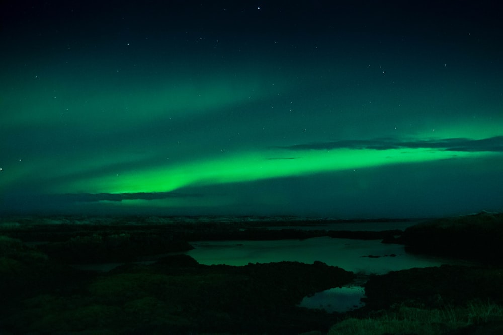 a green and black sky with the aurora in the background