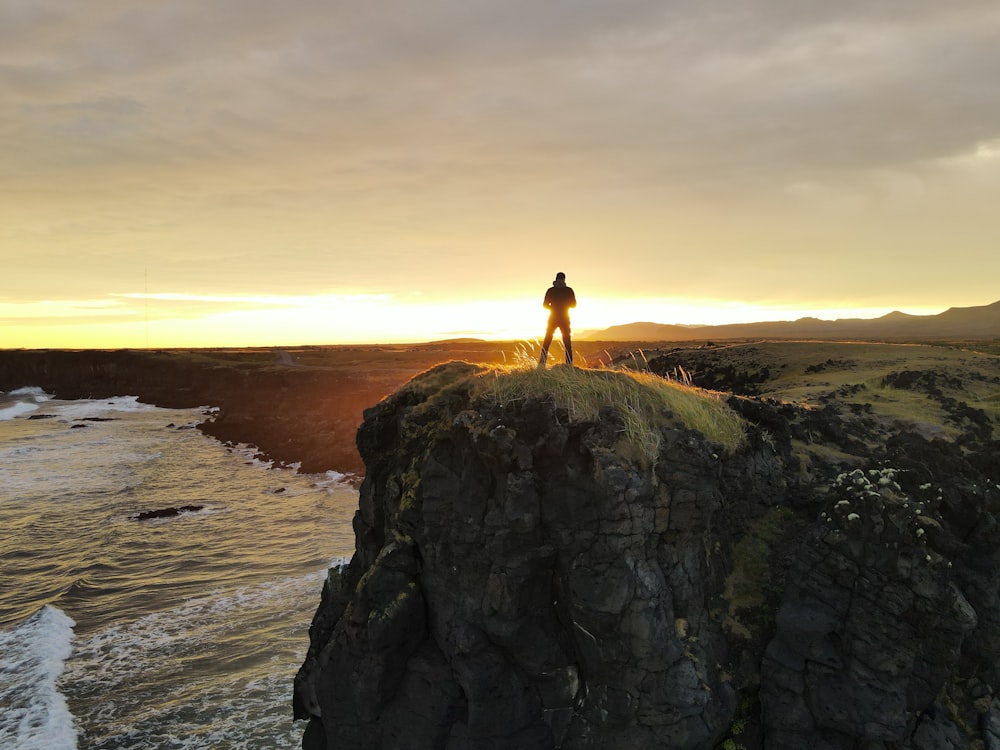 a person standing on top of a rock near the ocean