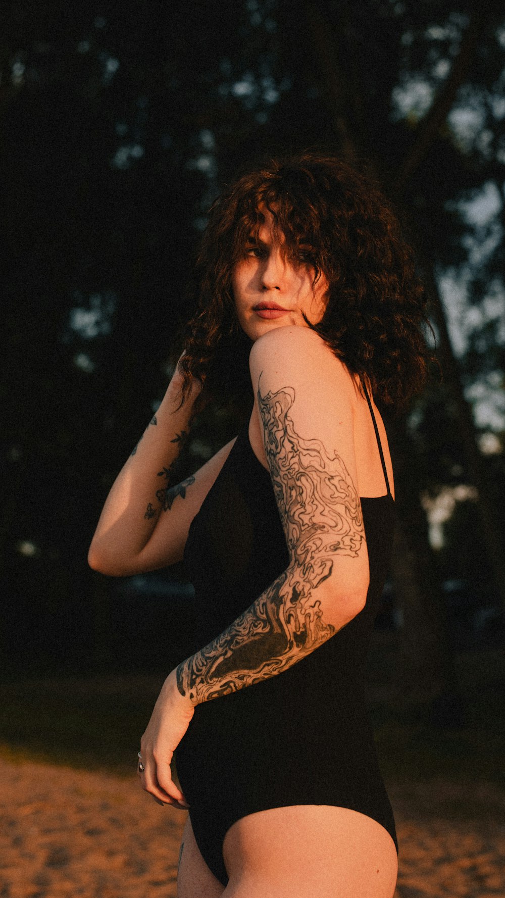 a woman in a black swimsuit with tattoos on her arm