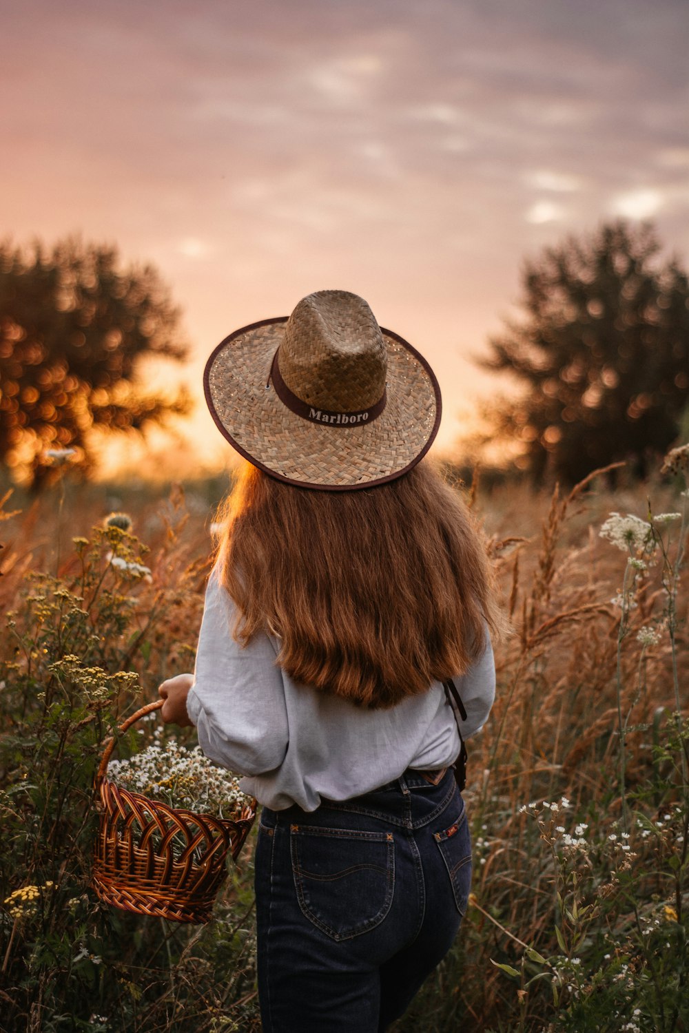 a woman in a hat is walking through a field