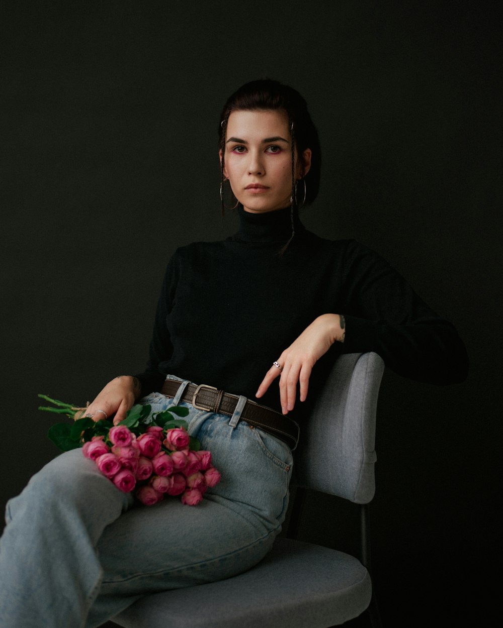 a woman sitting in a chair holding a bunch of flowers