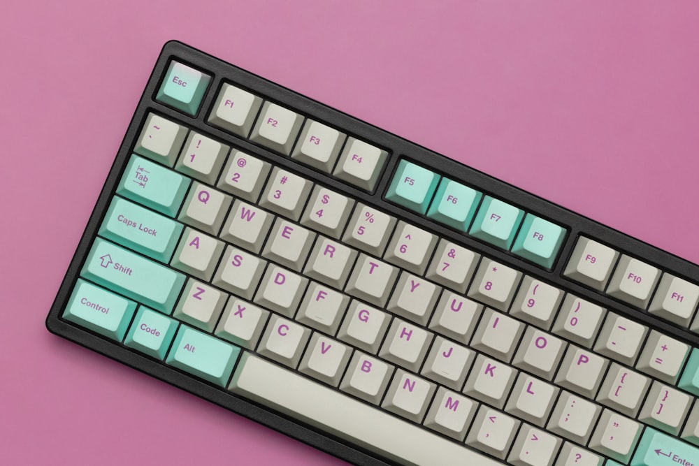Un primer plano de un teclado sobre un fondo rosa