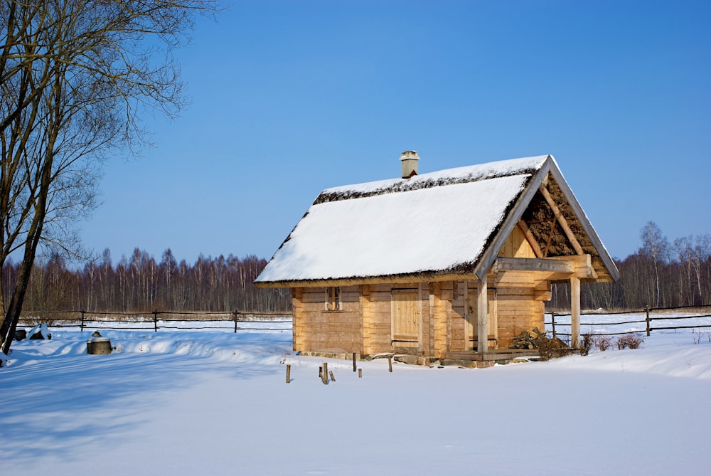 a small wooden cabin in the middle of a snowy field